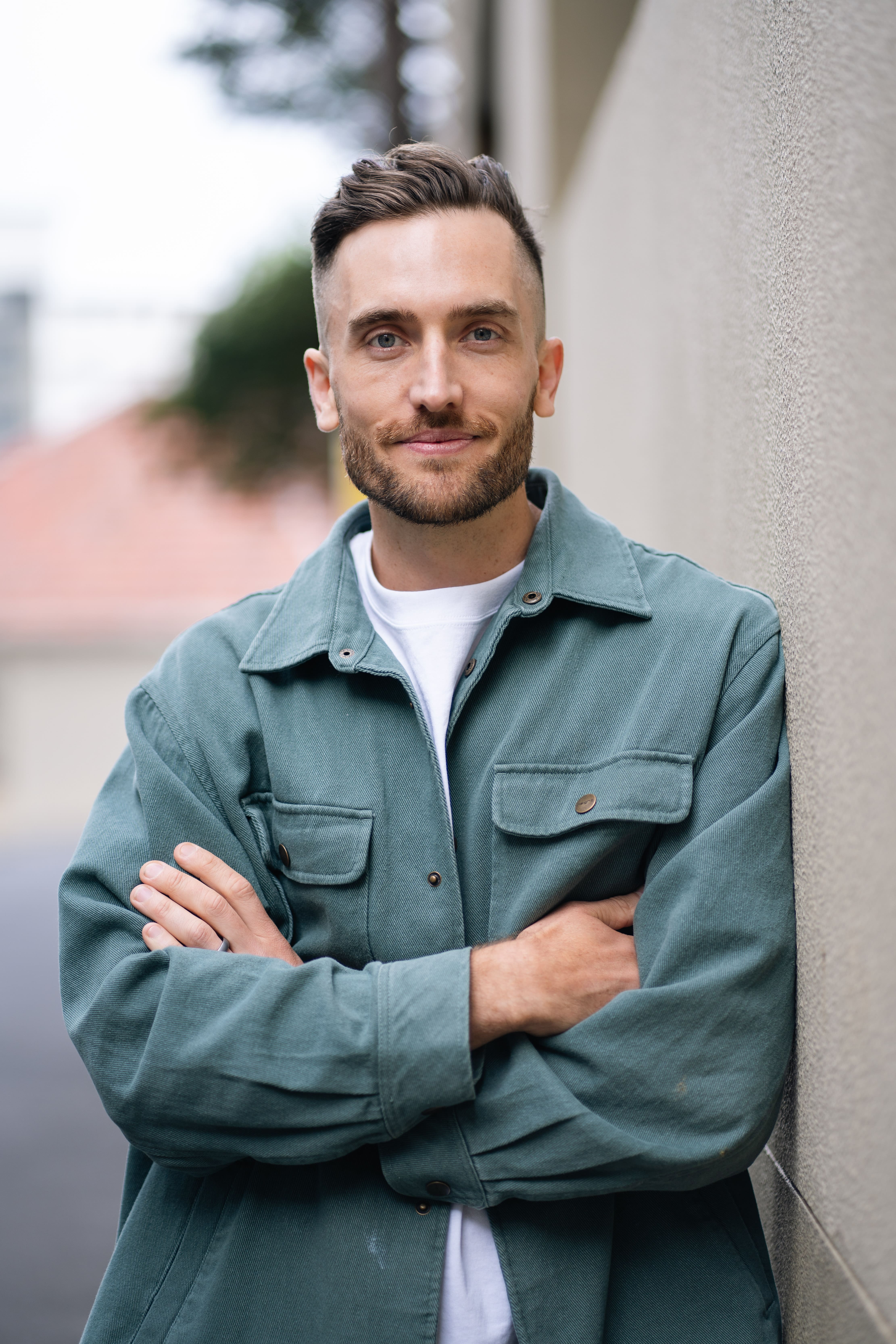 Andy Crebar leaning casually against a cream-coloured pillar in a navy suit