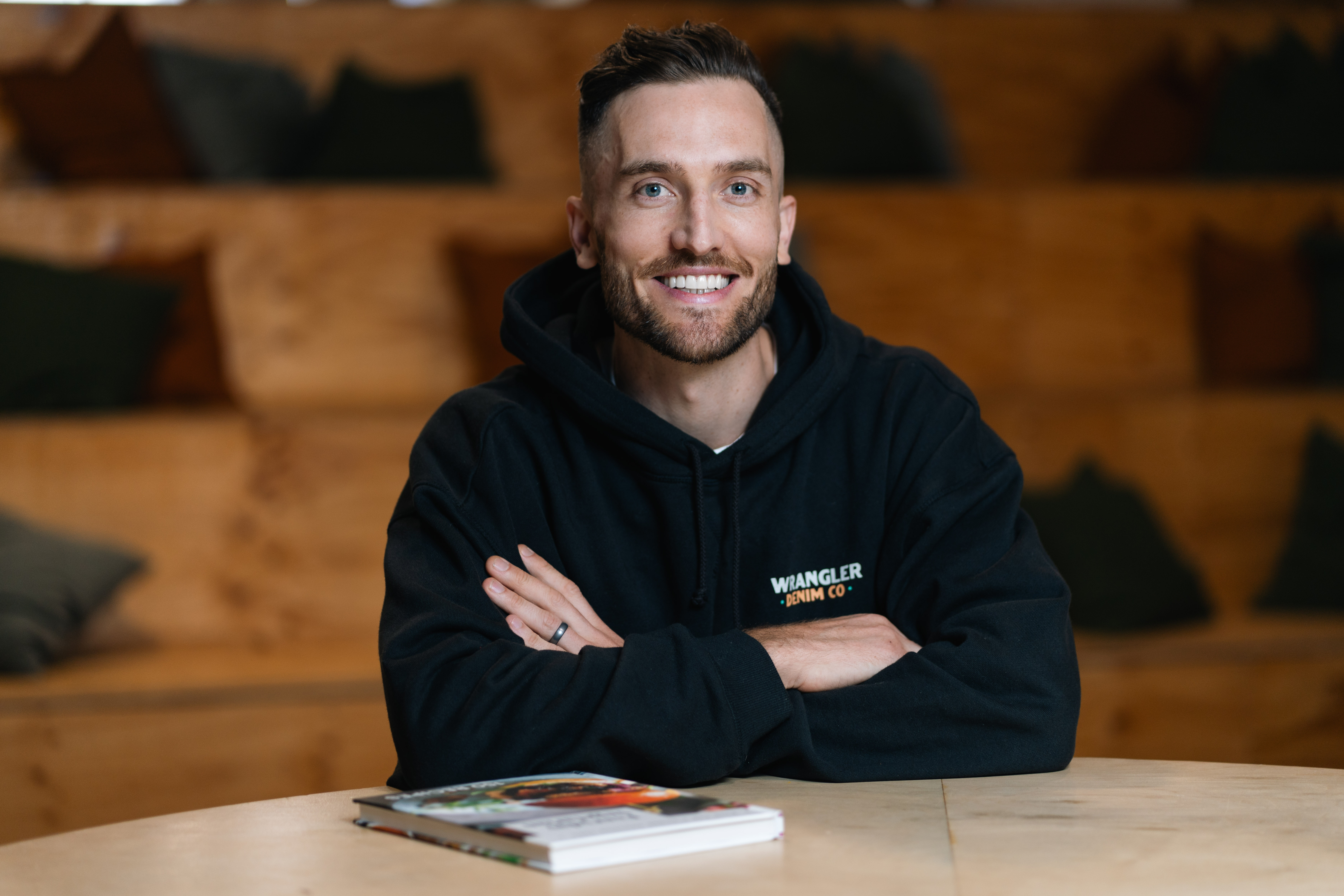 Andy Crebar wearing a black hoodie with arms crossed, seated in a creative workspace