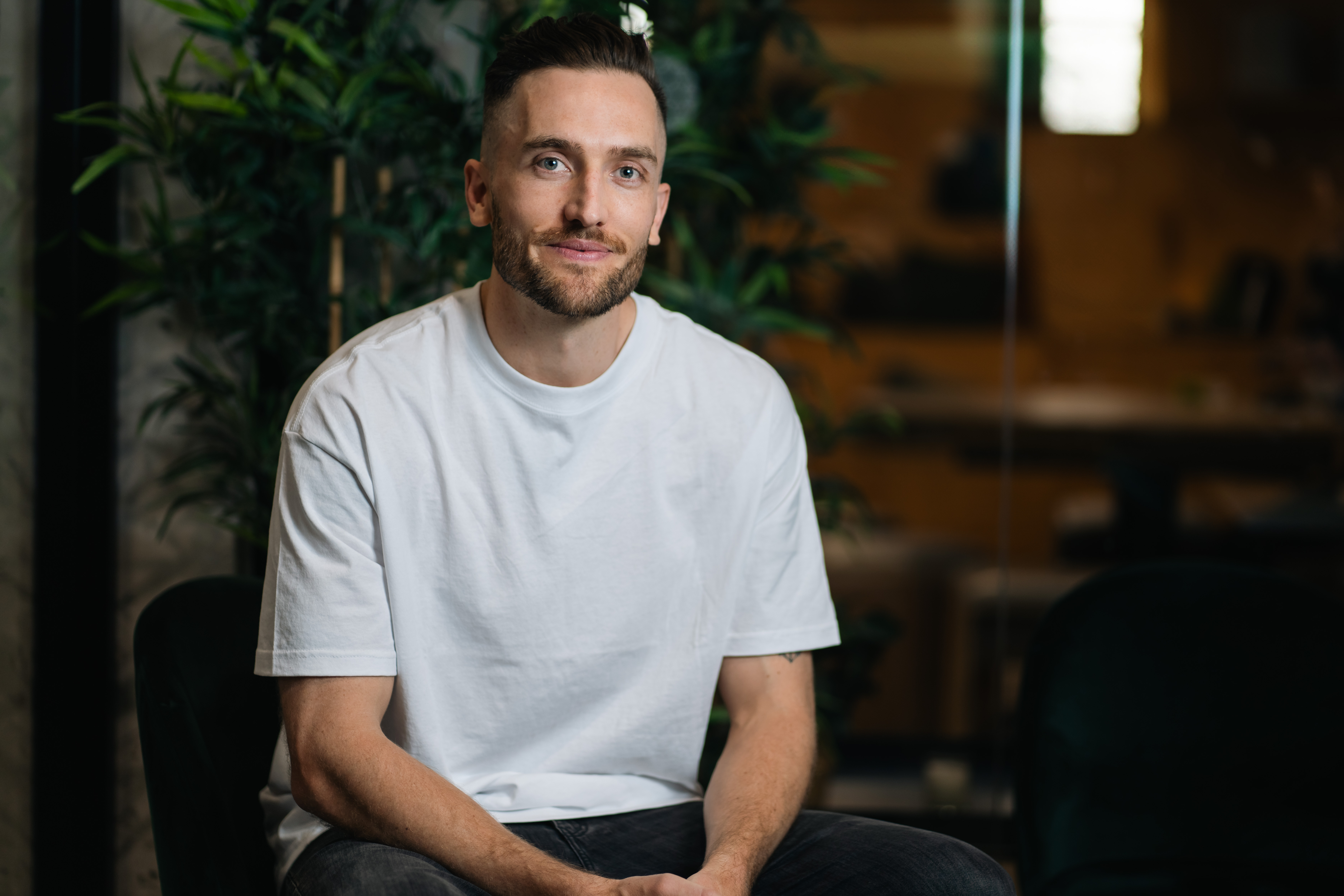Andy Crebar sitting in a modern office space wearing a white t-shirt